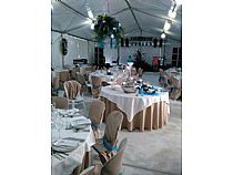 Conjunto de mesas, decoración y escenario para boda en carpa.